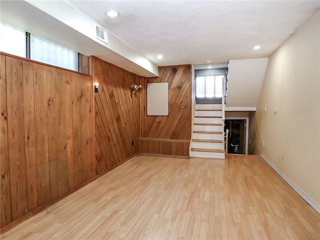 basement with wooden walls and light hardwood / wood-style flooring