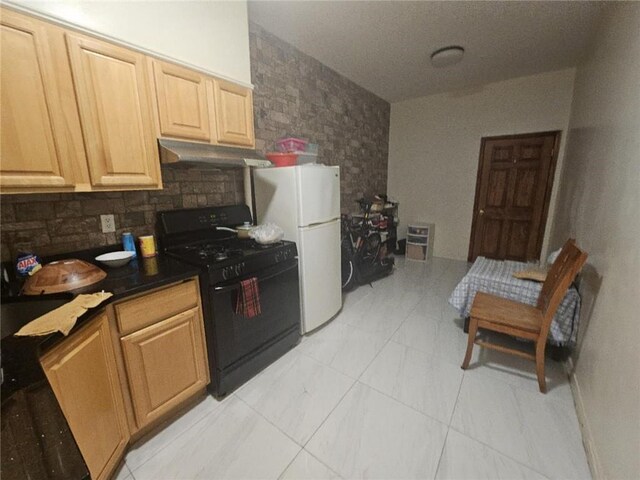 kitchen with black gas stove, white fridge, and backsplash