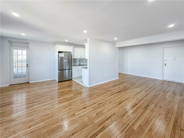 unfurnished living room with sink and light wood-type flooring