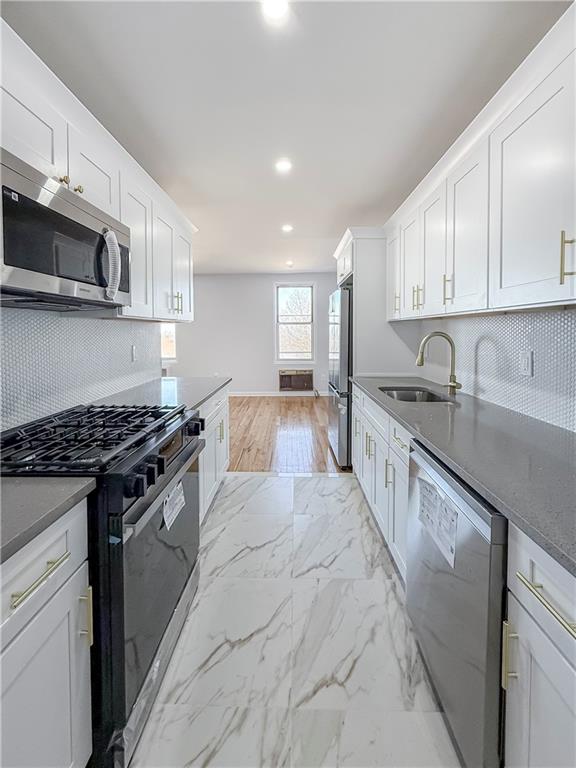 kitchen with white cabinetry, stainless steel appliances, sink, and backsplash