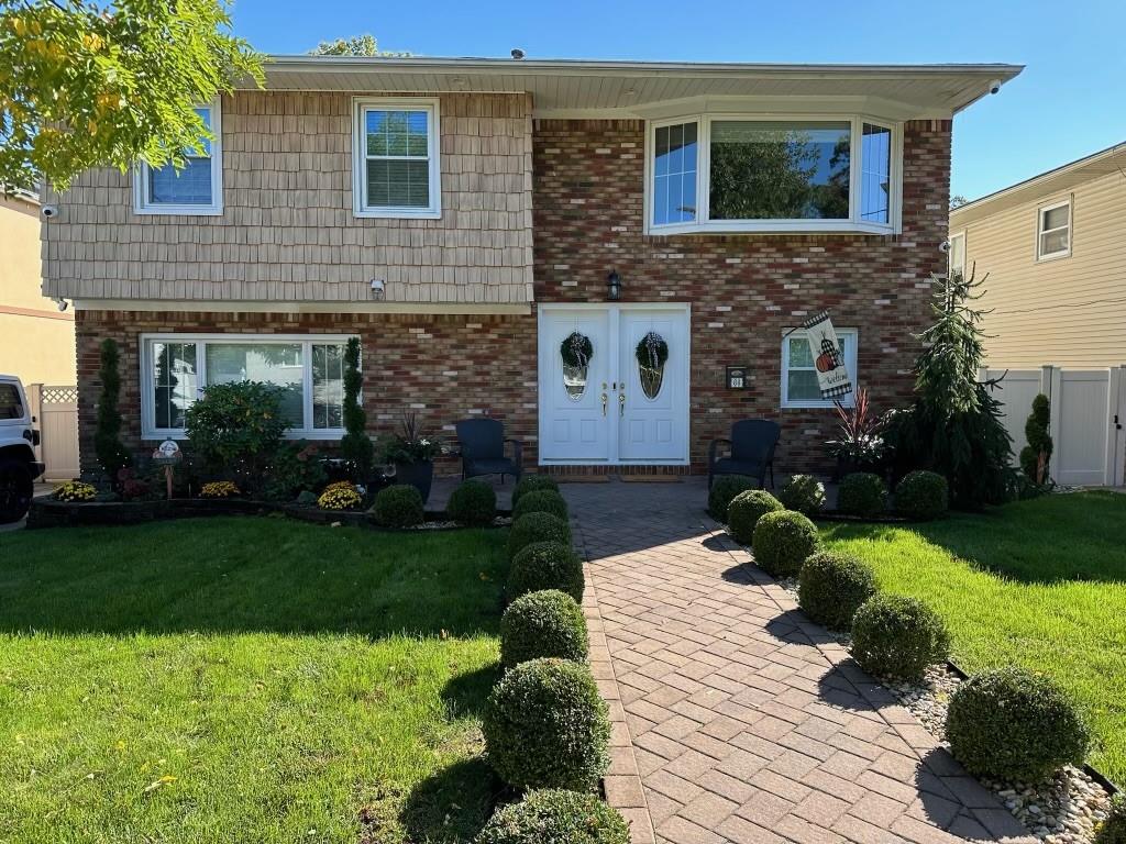 view of front of property with brick siding, a front lawn, and fence