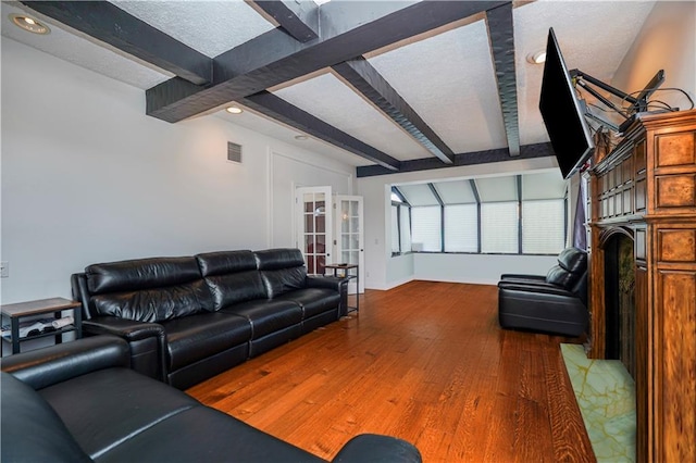 living room with visible vents, french doors, a textured ceiling, and wood finished floors