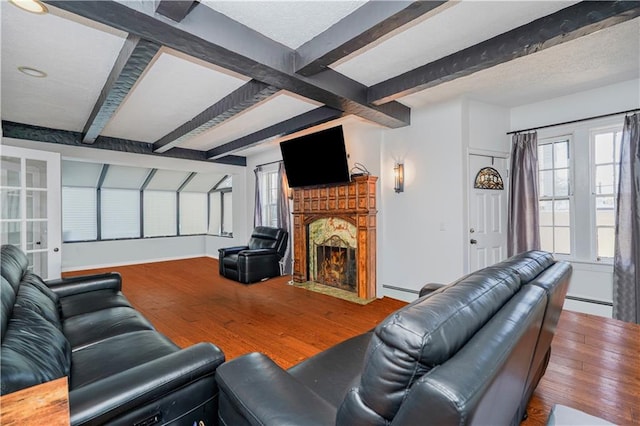 living room with beam ceiling, a fireplace with flush hearth, and wood finished floors