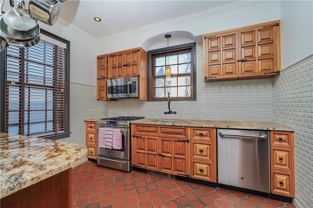 kitchen with light stone counters, a sink, appliances with stainless steel finishes, crown molding, and brown cabinets