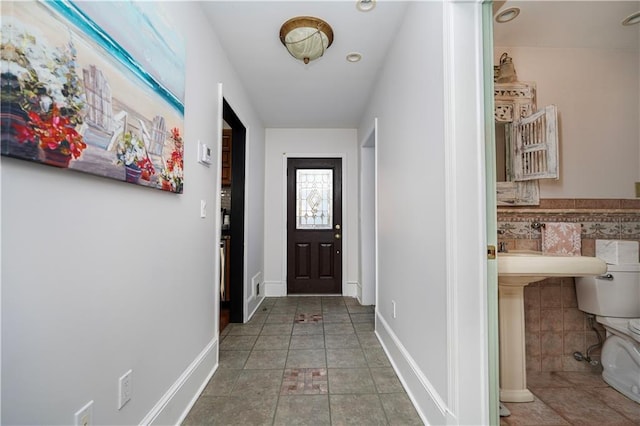 entryway featuring tile patterned floors, baseboards, tile walls, and wainscoting