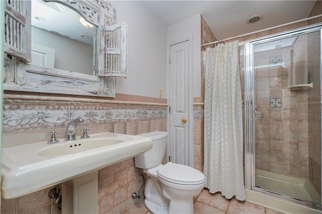 bathroom with tile walls, a stall shower, wainscoting, and tile patterned flooring