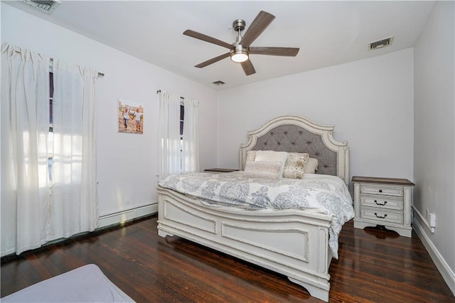 bedroom featuring visible vents, a baseboard heating unit, and wood finished floors