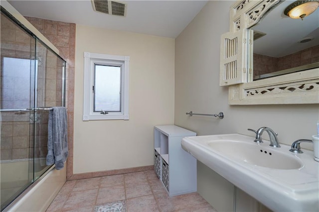 bathroom featuring baseboards, visible vents, shower / bath combination with glass door, a sink, and tile patterned floors