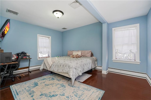 bedroom featuring visible vents, baseboards, baseboard heating, and wood finished floors