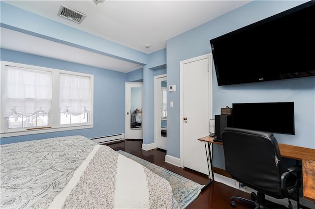 bedroom with visible vents, baseboard heating, baseboards, and wood finished floors