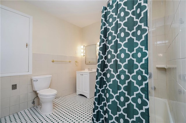 bathroom featuring tile patterned floors, toilet, tile walls, wainscoting, and vanity