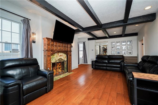 living room featuring a fireplace with flush hearth, beam ceiling, recessed lighting, a textured ceiling, and wood-type flooring