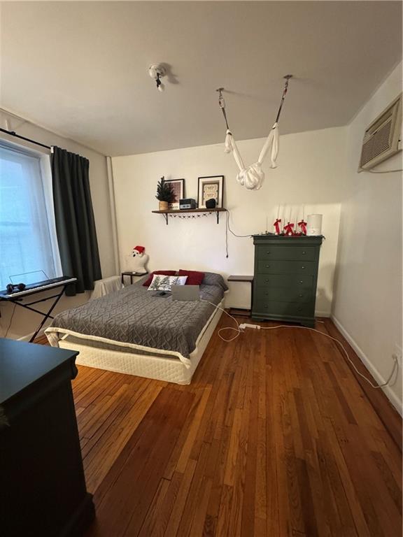 bedroom featuring dark hardwood / wood-style flooring and a wall unit AC