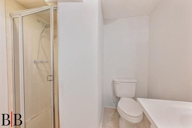 bathroom with toilet, tile patterned flooring, and a shower with door