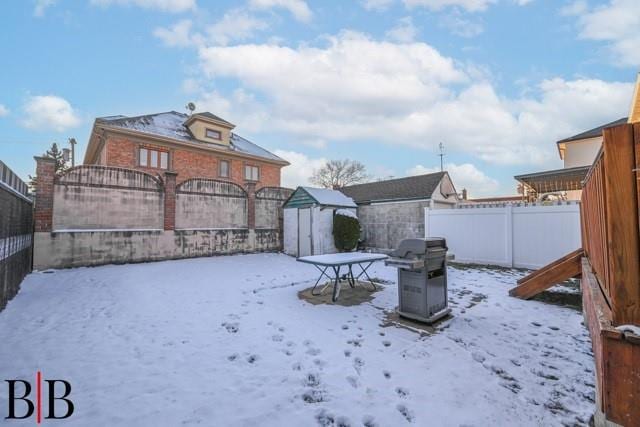 yard covered in snow featuring an outdoor fire pit and a storage unit