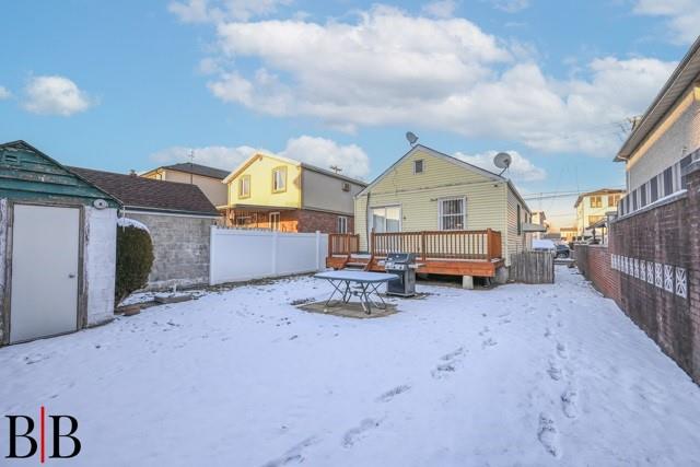 snowy yard with a shed and a deck