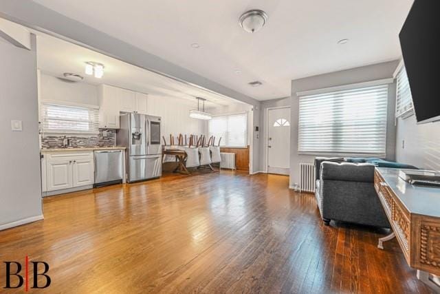 living room with radiator heating unit, sink, and wood-type flooring