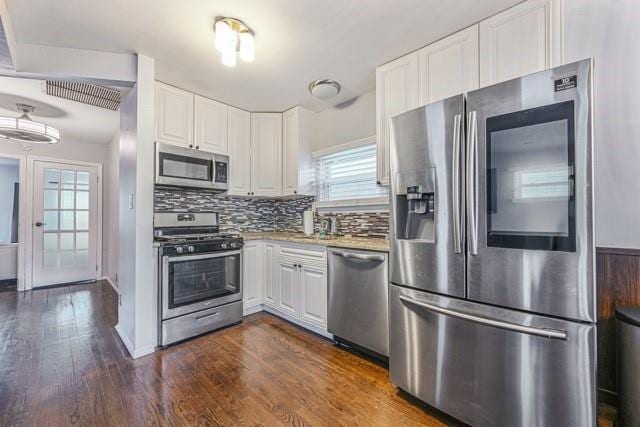 kitchen featuring tasteful backsplash, white cabinetry, appliances with stainless steel finishes, and dark hardwood / wood-style floors