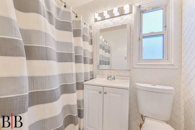 bathroom with vanity, tile walls, and toilet