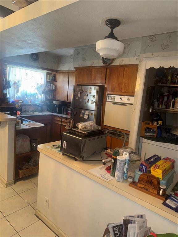 kitchen with light tile patterned floors, stainless steel fridge, and white oven