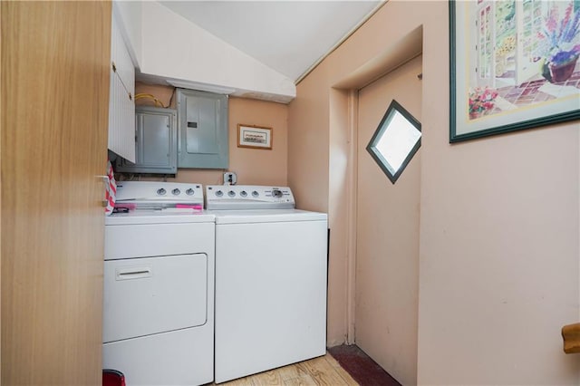 laundry area featuring light hardwood / wood-style flooring, electric panel, and washing machine and clothes dryer