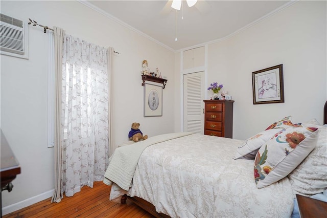 bedroom with a closet, ornamental molding, a ceiling fan, wood finished floors, and baseboards