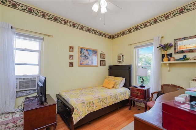 bedroom with ceiling fan, cooling unit, and wood finished floors