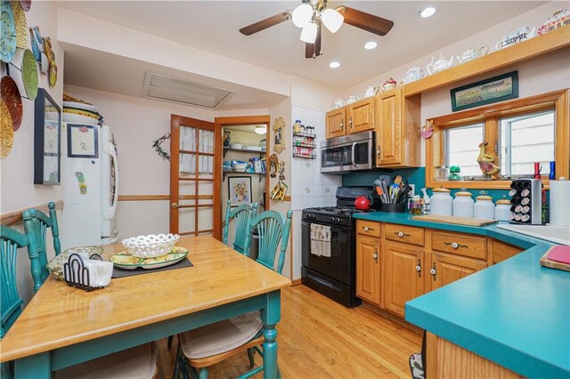 kitchen with black range with gas cooktop, light hardwood / wood-style flooring, ceiling fan, and white refrigerator