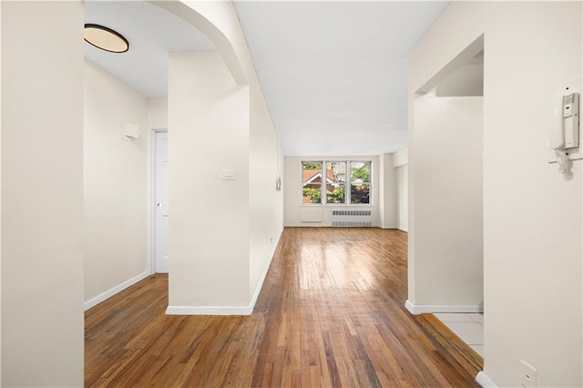 hall with radiator heating unit and hardwood / wood-style floors