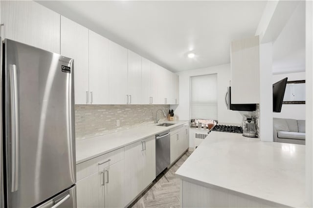 kitchen featuring sink, light parquet floors, appliances with stainless steel finishes, tasteful backsplash, and white cabinets