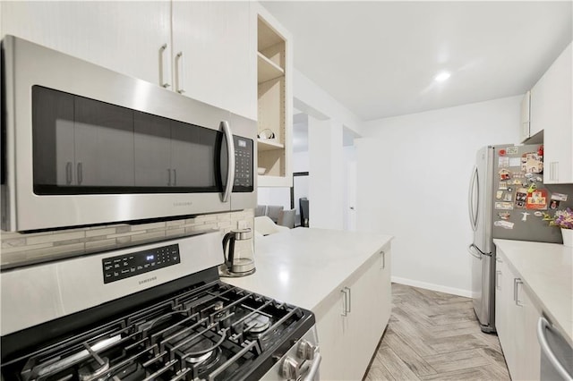 kitchen with tasteful backsplash, light parquet floors, white cabinets, and appliances with stainless steel finishes