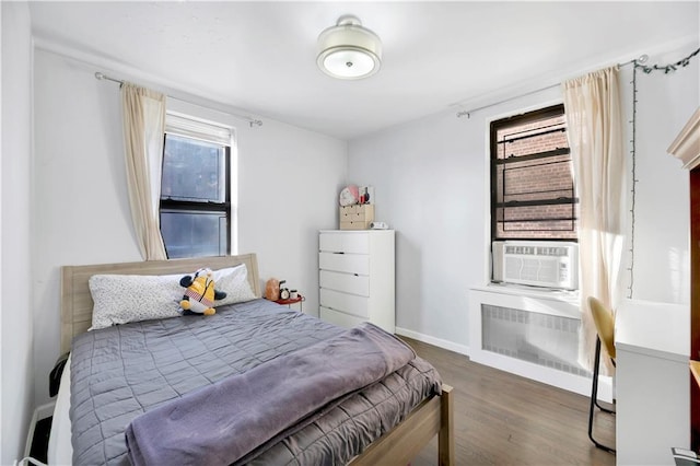 bedroom with wood finished floors, radiator heating unit, cooling unit, and baseboards