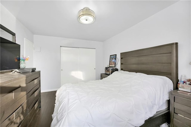 bedroom with dark hardwood / wood-style floors and a closet