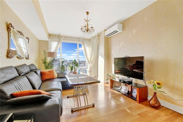 living room with a notable chandelier, an AC wall unit, and light wood-type flooring