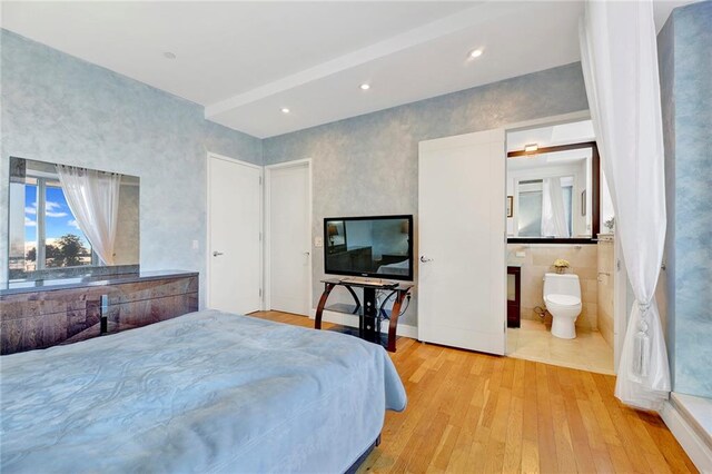 bedroom with ensuite bath and light hardwood / wood-style flooring