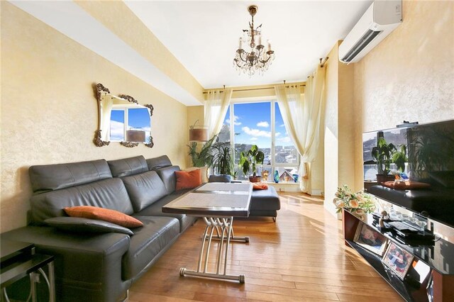 living room with hardwood / wood-style flooring, a wall mounted AC, and a notable chandelier