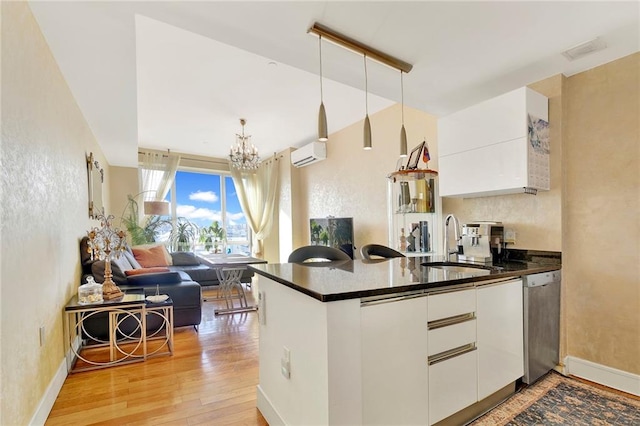 kitchen featuring white cabinetry, dishwasher, a wall mounted AC, and decorative light fixtures