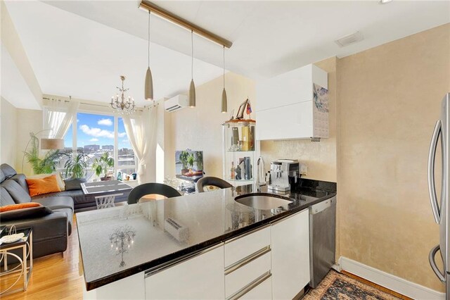 kitchen featuring white cabinetry, stainless steel appliances, decorative light fixtures, and sink