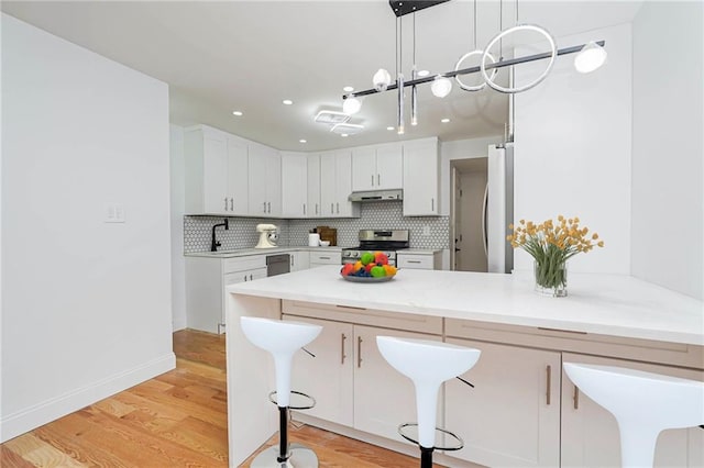 kitchen with stainless steel appliances, kitchen peninsula, white cabinets, and a kitchen bar