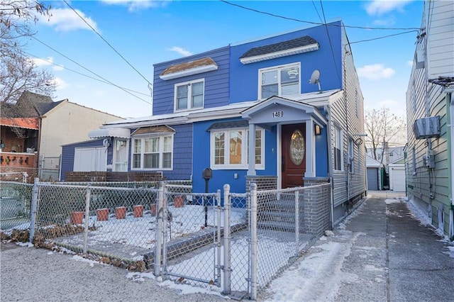 view of front of house with a fenced front yard, a garage, an outdoor structure, and a gate