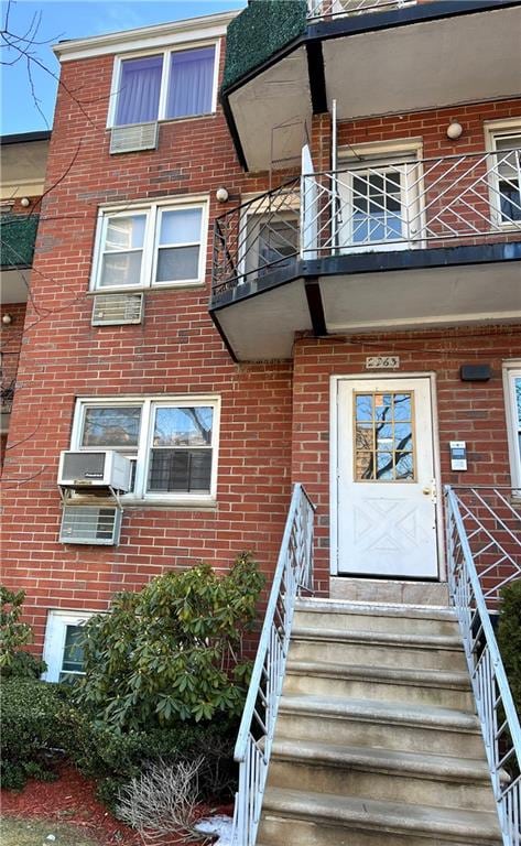 property entrance featuring a balcony, cooling unit, and brick siding