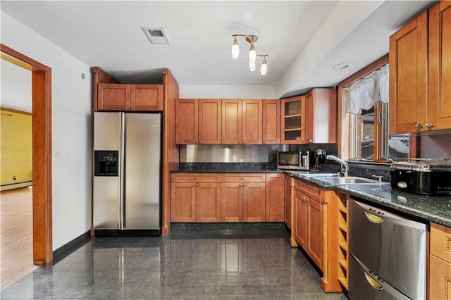 kitchen featuring a baseboard heating unit, appliances with stainless steel finishes, sink, and dark stone counters