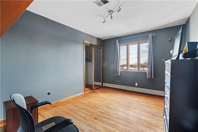 interior space with rail lighting, baseboard heating, and light hardwood / wood-style floors