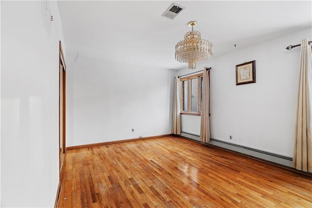 empty room featuring baseboard heating, an inviting chandelier, and light hardwood / wood-style flooring