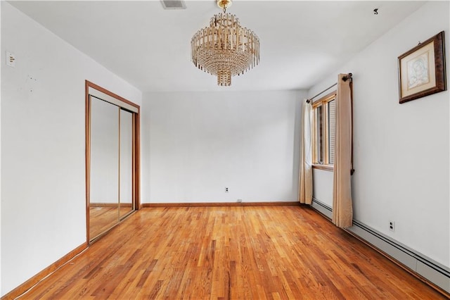 unfurnished bedroom with light hardwood / wood-style floors, an inviting chandelier, baseboard heating, and a closet