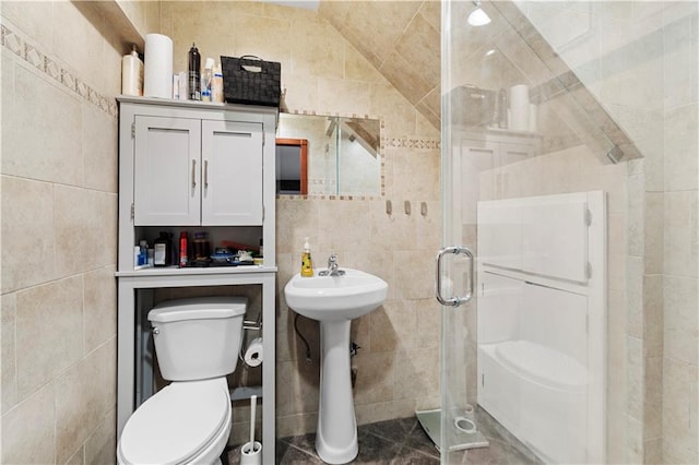 bathroom featuring vaulted ceiling, sink, tile walls, toilet, and a shower with door