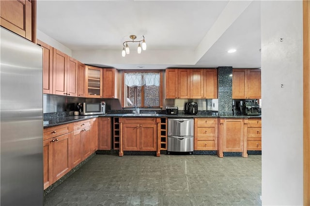 kitchen with stainless steel appliances, sink, backsplash, and dark stone counters