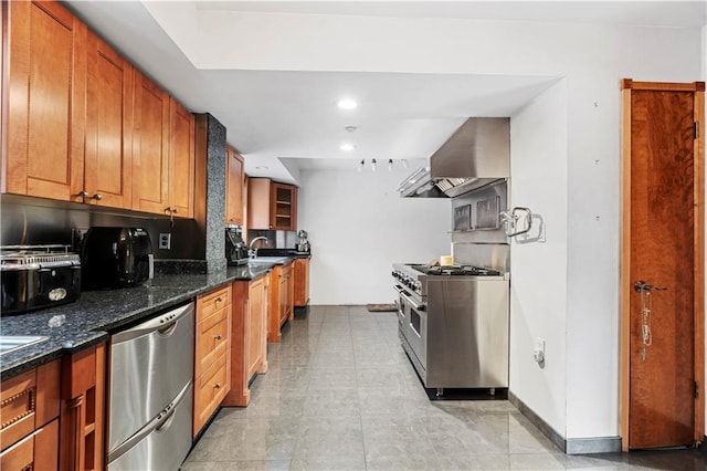 kitchen with wall chimney range hood, sink, appliances with stainless steel finishes, dark stone countertops, and decorative backsplash