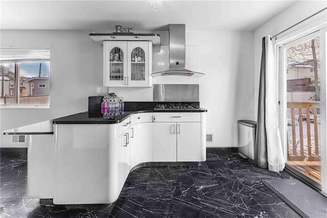 kitchen with white cabinetry, kitchen peninsula, black gas cooktop, and wall chimney exhaust hood