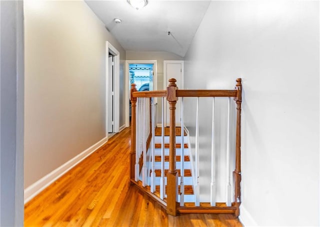 staircase with wood-type flooring and vaulted ceiling